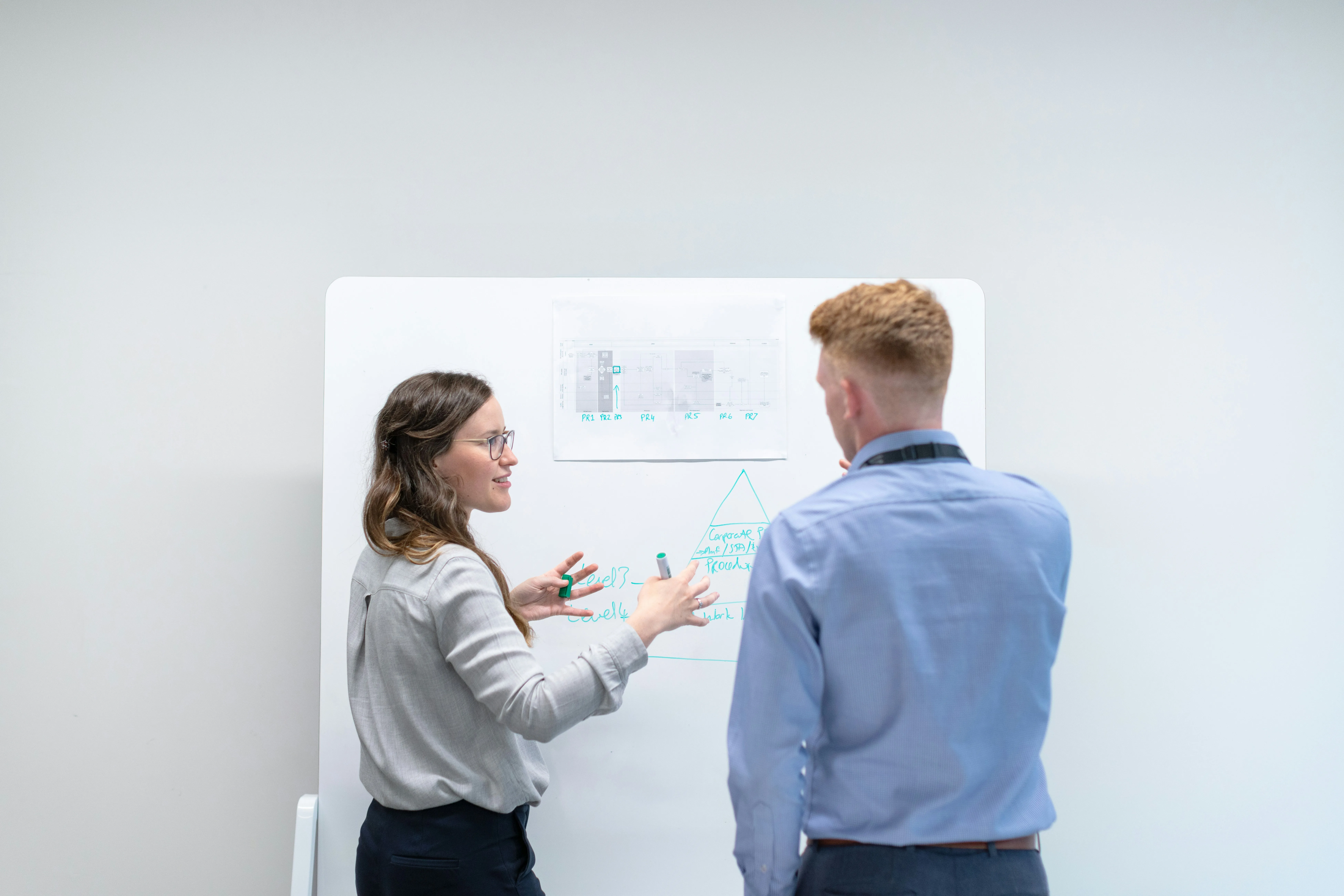 Two engineers review notes on a whiteboard. Photo by This is Engineering.